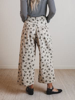 Person wearing a striped shirt and floral wide-leg pants on a plain background