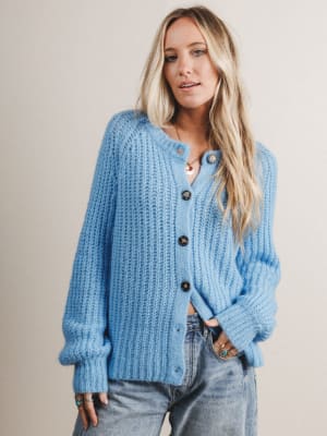 Woman wearing a blue knitted cardigan against a plain background