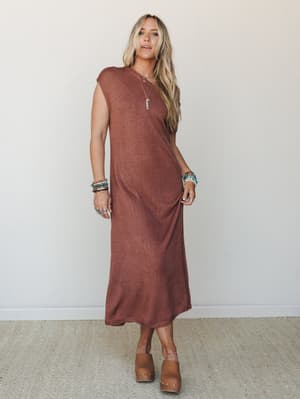 A relaxed knit midi dress in warm rust styling with layered boho jewelry and wood-heeled clogs — the kind of effortless outfit that works just as hard at brunch as it does on a slow weekend walk.