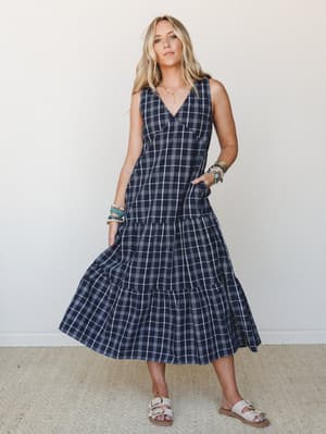 A navy plaid midi dress with a flowy tiered skirt styled with stacked turquoise bracelets and white buckle sandals — effortless and a little unexpected, in the best way.