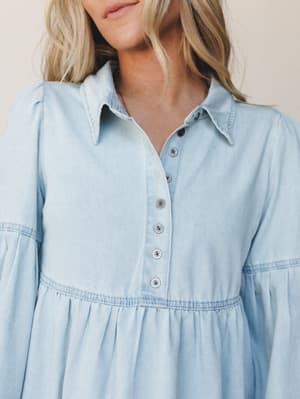 A soft chambray babydoll dress shot close-up, with a relaxed feminine feel — the kind of piece that looks just as easy on a coffee run as it does at a weekend farmers market.