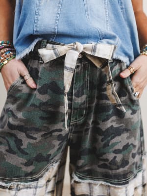 Person wearing camouflage shorts with a plaid shirt and denim jacket.