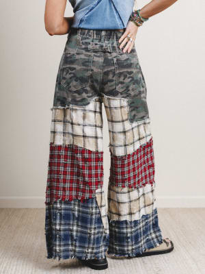 Person wearing patchwork pants with a neutral background