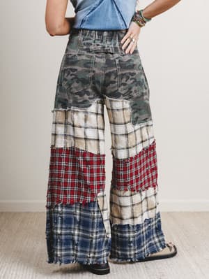 Person wearing patchwork pants with a neutral background