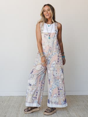 A wide-leg patchwork floral overall styled over a white lace top with turquoise jewelry and platform sandals — the kind of outfit that looks effortless but is clearly very much on purpose.