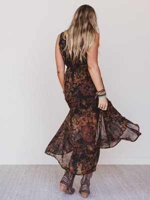 Woman wearing a long, patterned dress against a plain background