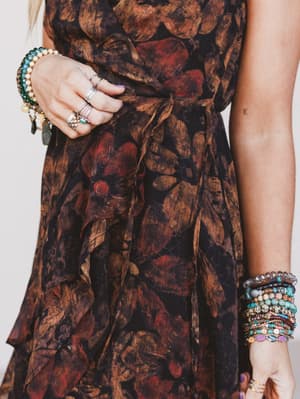 Close-up of a person wearing a patterned dress with jewelry on a plain background
