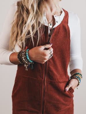 Person wearing a brown corduroy vest over a white shirt with visible jewelry.
