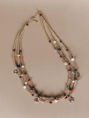 Multistrand beaded necklace with charms on a beige background