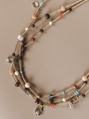 Multistrand necklace with beads and charms on a beige background