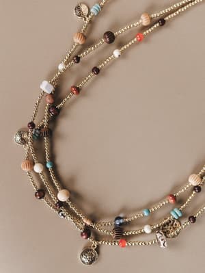 Multistrand necklace with beads and charms on a beige background