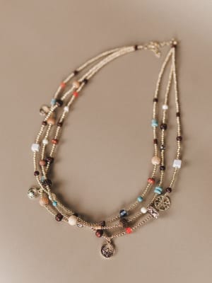 Multistrand beaded necklace with charms on a beige background