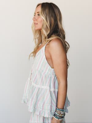 A breezy striped tank top with lace trim and ruffle hem photographed in profile — the kind of top that looks equally at home on a sunny patio or a weekend farmers market run.