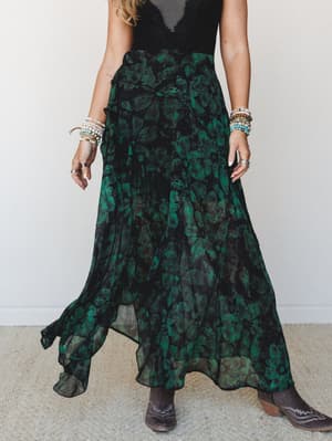 A flowy floral maxi skirt in deep emerald and black paired with a black lace top and western boots — the kind of outfit that makes a Tuesday feel like it deserves a better story.