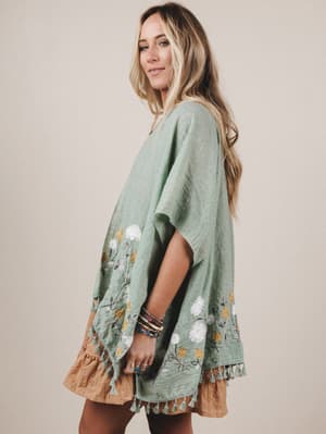 Woman wearing a green embroidered dress with a beige background