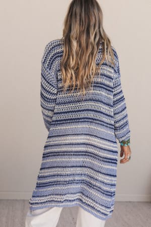 back view of woman wearing a long blue and white Soul Synced Striped Cardigan against a plain background