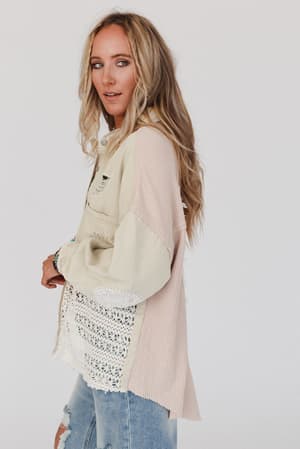 A woman with long blonde hair wears the Way Home Patch Detail Shacket in beige over a beige and pink shirt with lace details and ripped blue jeans, standing against a plain white background, looking slightly to the side.