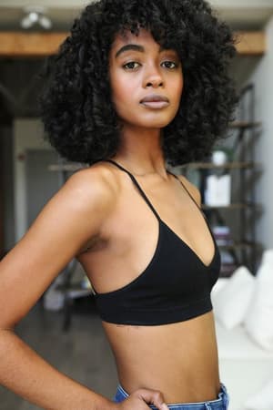 A woman with curly hair wears a black garment and the Crescent Moon Tattoo Bralette in black.