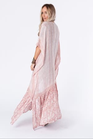 A woman with long blonde hair models the Paisley Tapestry Free Flow Duster Kimono in Blush, standing sideways and looking over her shoulder against a plain white background.