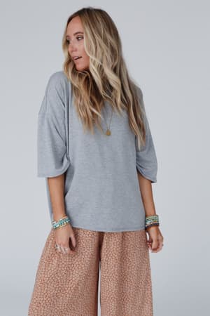 A woman wearing The Nest Must Have High Low Tee in Heather Gray and shorts, styled in a relaxed boho vibe.