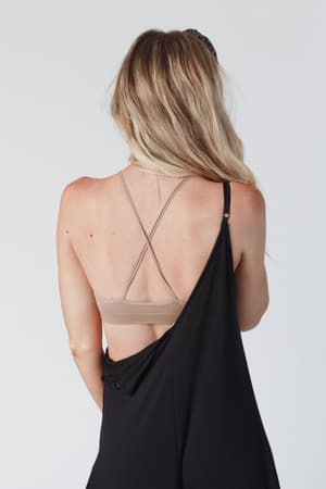 A woman with long blonde hair is shown from behind, wearing the Double Take High Neck Bralette in Mocha and a black off-the-shoulder garment that reveals her back and shoulders against a plain, light background.