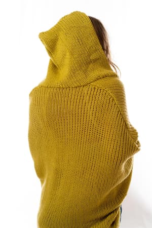 A person faces away from the camera, wearing the Cozy Hooded Cardigan - Mustard. The thick knit texture and hoodie stand out against a plain white background, with their hair partially visible.