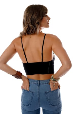 A woman with shoulder-length brown hair, facing away, wears a black Floral Textured Padded Bralette and blue jeans. She has bracelets on her left wrist and her hands in her back pockets against a white background.