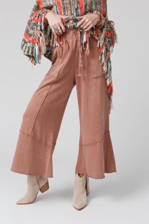 Wearing the Feeling Good Wide Leg Pant in Faded Rust, a multicolored fringed sweater, and light beige ankle boots, this casual boho outfit is modeled with the face not visible.