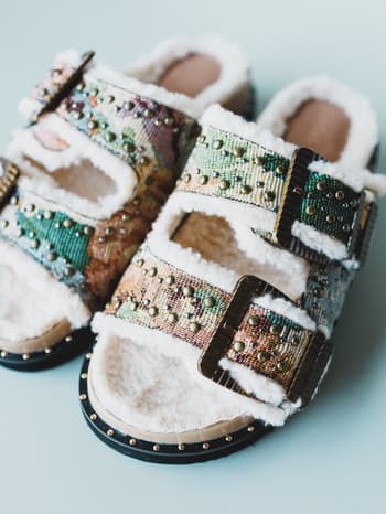 Decorative slippers with colorful patterns and fur on a light blue background
