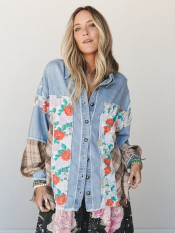 A patchwork denim shacket layered with floral and plaid fabric panels worn open over a dark floral skirt — the kind of piece that looks like it was assembled from your most-loved vintage finds.