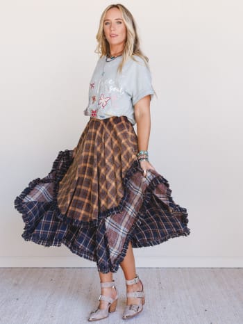 Woman wearing a Sand Dancer plaid skirt and graphic t-shirt against a white background