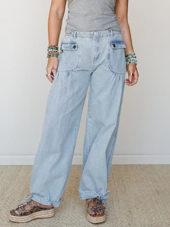 Light wash wide-leg denim pants with relaxed, barrel-style volume — styled with a fitted grey tee, stacked turquoise bracelets, and leopard platform sandals for that effortlessly collected, off-duty boho look.