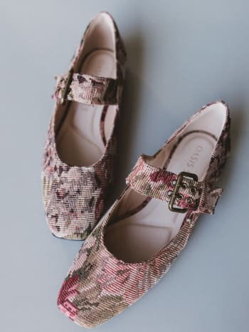 Pair of floral-patterned shoes with buckles on a gray background