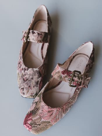 Pair of floral-patterned shoes with buckles on a gray background