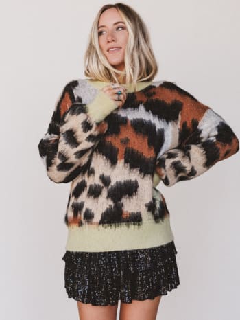 Person wearing a patterned sweater and black skirt against a white background