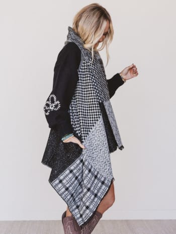 Woman wearing a black and white patterned dress with a plain background