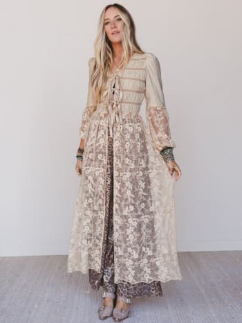 Woman wearing a long, floral-patterned duster with sheer sleeves against a white background