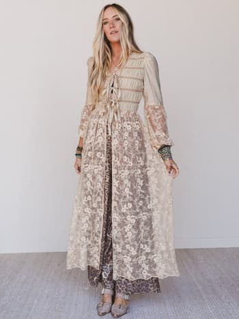 Woman wearing a long, floral-patterned duster with sheer sleeves against a white background