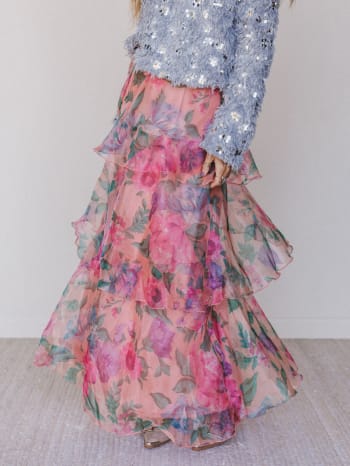 Person wearing a floral skirt and sequined top against a plain background