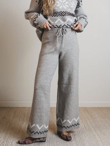 Person wearing a gray knit outfit with patterned details on a neutral background