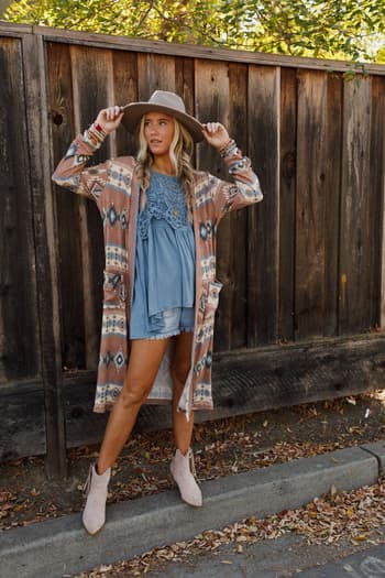 Multi / Woman in a patterned Santa Fe Rose Duster Cardigan and denim dress standing against a wooden fence.